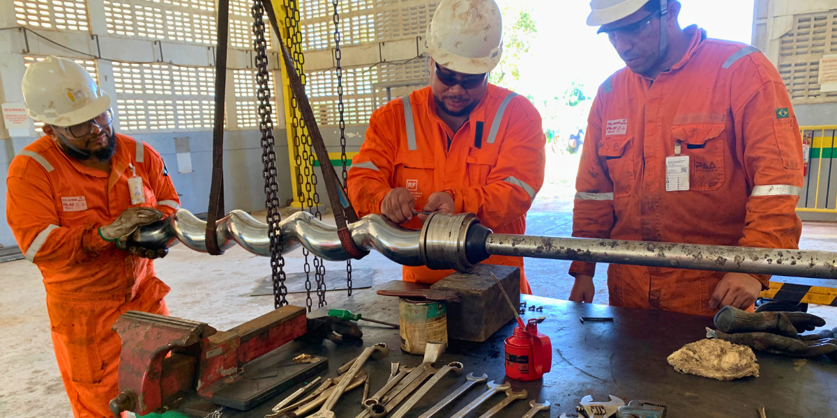 Equipe verificando equipamento industrial durante processo de manutenção preventiva industrial.